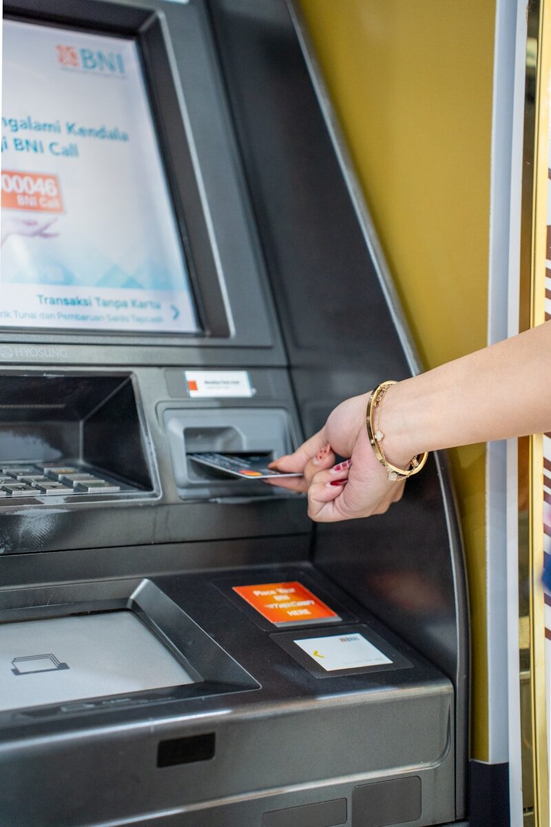 A hand inserts a card into an atm machine.